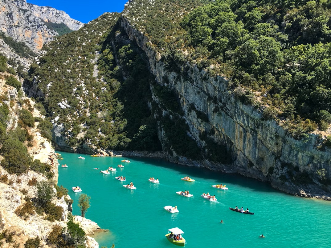 The bright turquoise Verdon River flowing through steep white limestone cliffs under a clear blue sky.