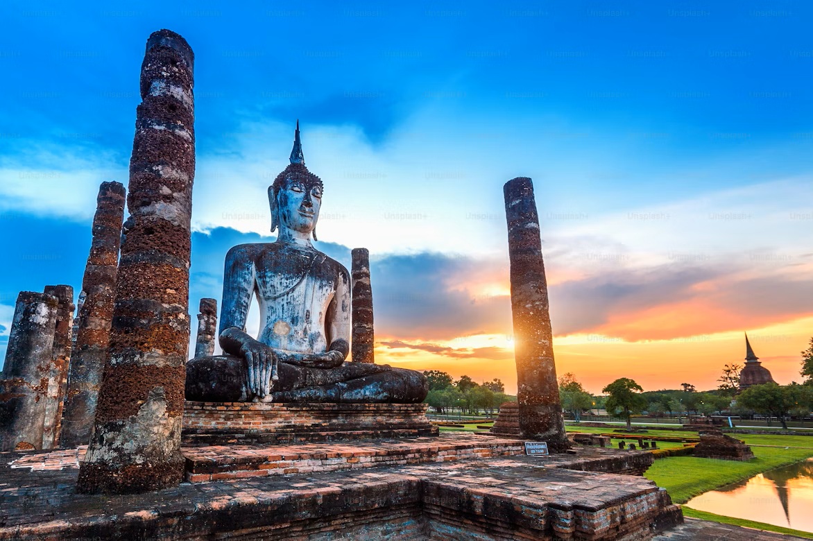 Tourist riding a bicycle through the serene ruins of Sukhothai Historical Park at dusk