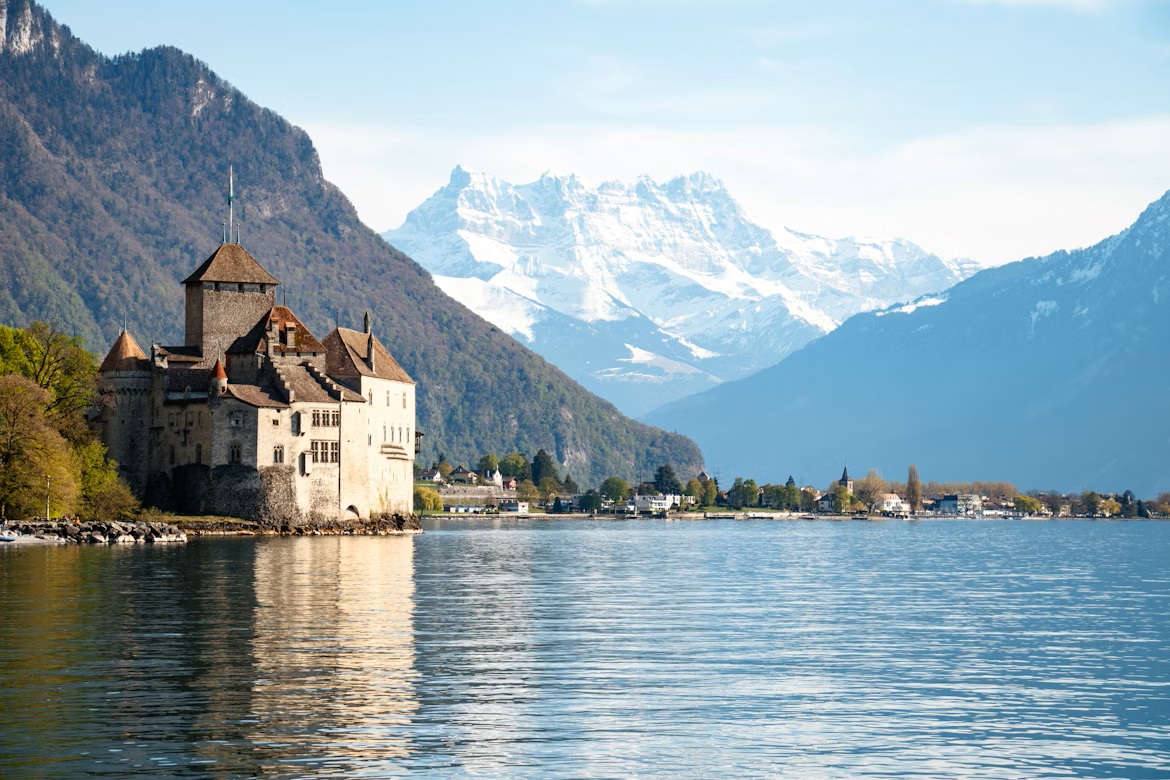 The medieval island fortress of Chillon Castle on the shores of Lake Geneva with a dramatic Alpine mountain backdrop near Montreux.