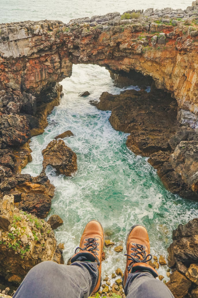 Waves crashing through a natural stone archway at Boca do Inferno near Cascais.