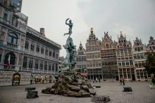 Panoramic view of the Antwerp skyline featuring the Cathedral of Our Lady and the MAS Museum reflecting in the Scheldt river at sunset