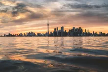 Panoramic sunset view of the Toronto skyline and CN Tower reflecting in the waters of Lake Ontario.