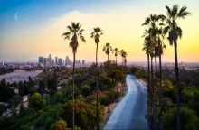Los Angeles skyline at sunset with palm trees, gateway to the ultimate Pacific Coast Highway road trip to San Francisco