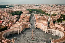 Panoramic view of Rome at sunset, showing the historic cityscape with domes, ancient buildings, and the Tiber River.