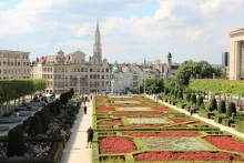 Panoramic view of Brussels city center with Grand Place square, ornate historic guild houses, and city skyline at sunset.