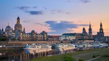 Panoramic view of Dresden skyline with historic baroque architecture, church domes, and the Elbe River at sunset in Germany.
