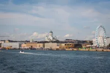 Panoramic view of Helsinki waterfront with Nordic architecture, harbor ferries, cathedral domes, and Baltic Sea reflections under soft evening light in Finland.