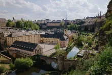 Panoramic view of Luxembourg City with dramatic cliffside architecture, historic old town buildings, bridges, and green valleys surrounding the skyline.