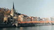 Panoramic view of Lyon with the Rhône and Saône rivers, historic Old Town rooftops, Basilica of Notre-Dame de Fourvière on the hill, and warm evening light over the city in France.