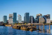 Panoramic view of Oslo waterfront with modern Scandinavian architecture, Oslo Fjord, opera house, and city skyline under soft evening light in Norway.