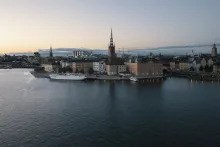 Panoramic view of Stockholm city skyline with historic Gamla Stan rooftops, waterfront islands, and golden light reflecting across the Baltic Sea.
