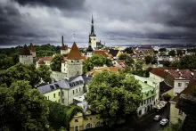 Panoramic view of Tallinn, Estonia featuring the medieval Old Town skyline with red rooftops, church spires, and the Baltic Sea coastline under soft morning light.