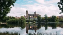 Panoramic view of Salamanca, Spain, featuring golden sandstone buildings, historic university architecture, Plaza Mayor, and warm evening light over the old city skyline.