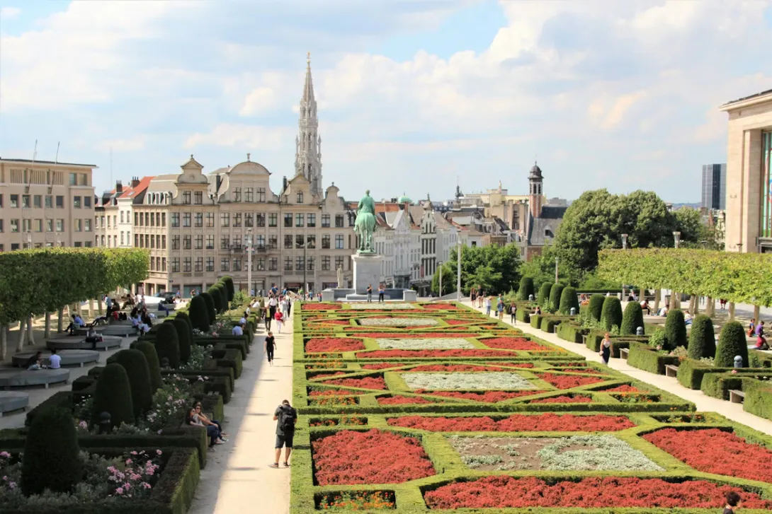Panoramic view of Brussels city center with Grand Place square, ornate historic guild houses, and city skyline at sunset.