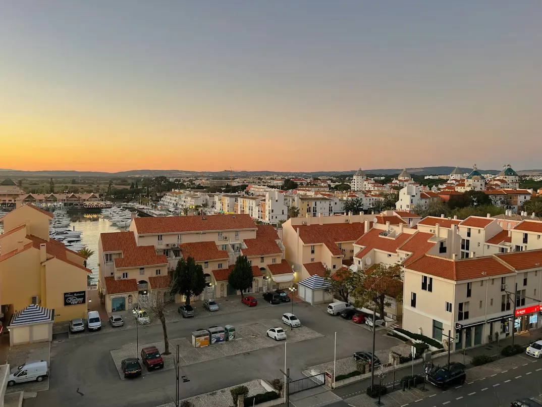 Panoramic view of Faro old town with whitewashed buildings, historic rooftops, palm trees, and the Algarve coastline in Portugal.