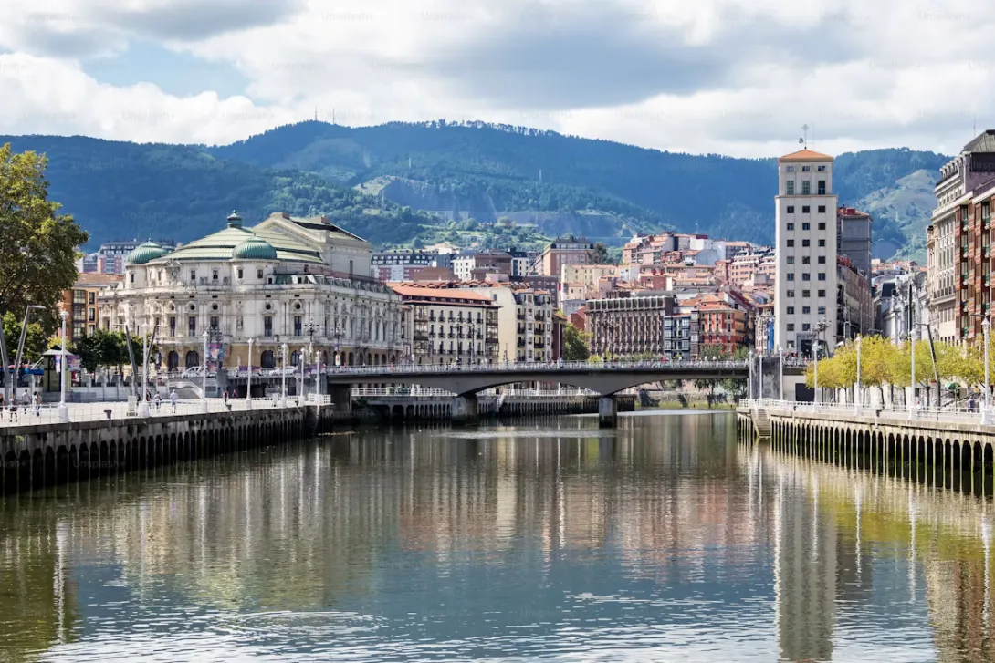 Panoramic view of Innsbruck, Austria featuring colorful alpine buildings, the Inn River, historic old town rooftops, and dramatic snow-capped mountains surrounding the city.