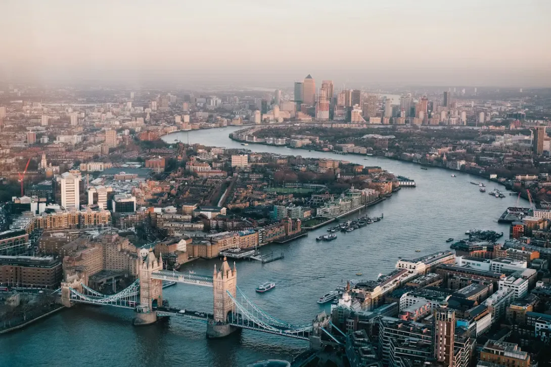 Panoramic view of the London skyline with the River Thames, Tower Bridge, and modern skyscrapers at sunset in England.
