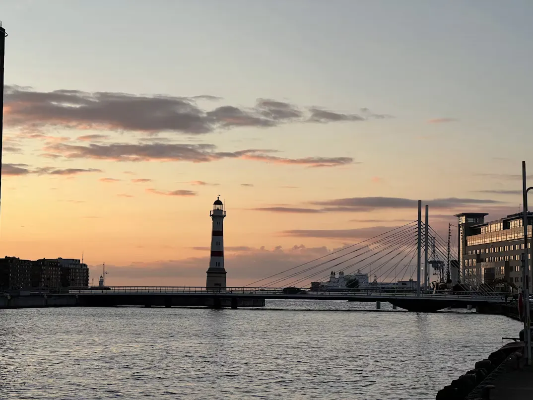 Panoramic view of Malmö city skyline with modern waterfront architecture, harbor, and the Øresund Bridge stretching across the sea in the distance.