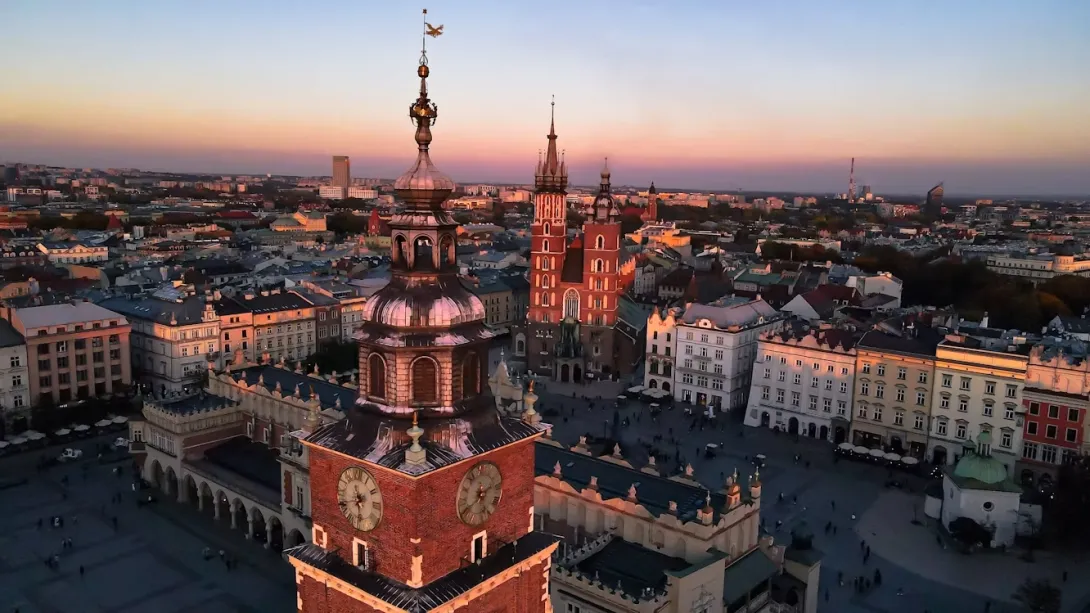 Panoramic view of Krakow, Poland, featuring the historic Old Town, St. Mary’s Basilica towers, Wawel Castle overlooking the Vistula River, colorful rooftops, and centuries-old architecture under a bright daytime sky.