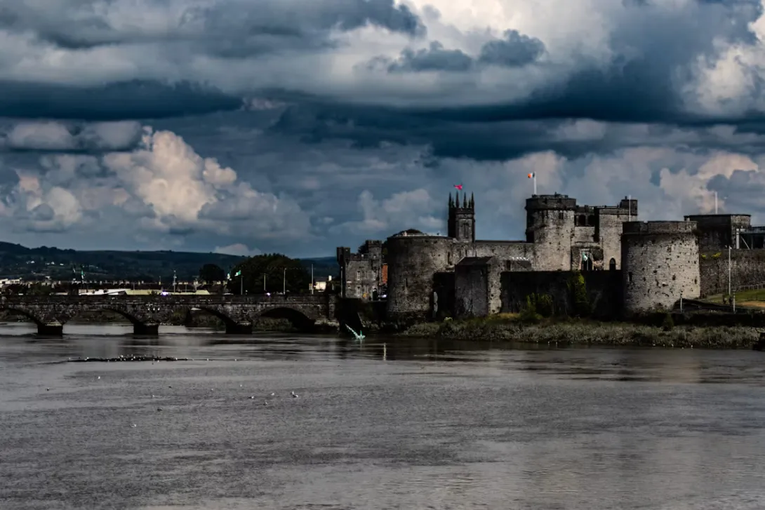 Panoramic view of Limerick, Ireland, showcasing the River Shannon, King John's Castle, historic city center, and elegant bridges under a bright Irish sky.