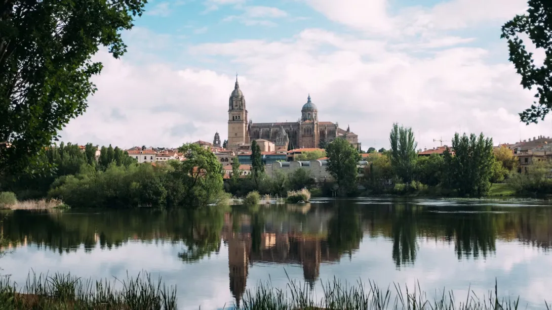 Panoramic view of Salamanca, Spain, featuring golden sandstone buildings, historic university architecture, Plaza Mayor, and warm evening light over the old city skyline.